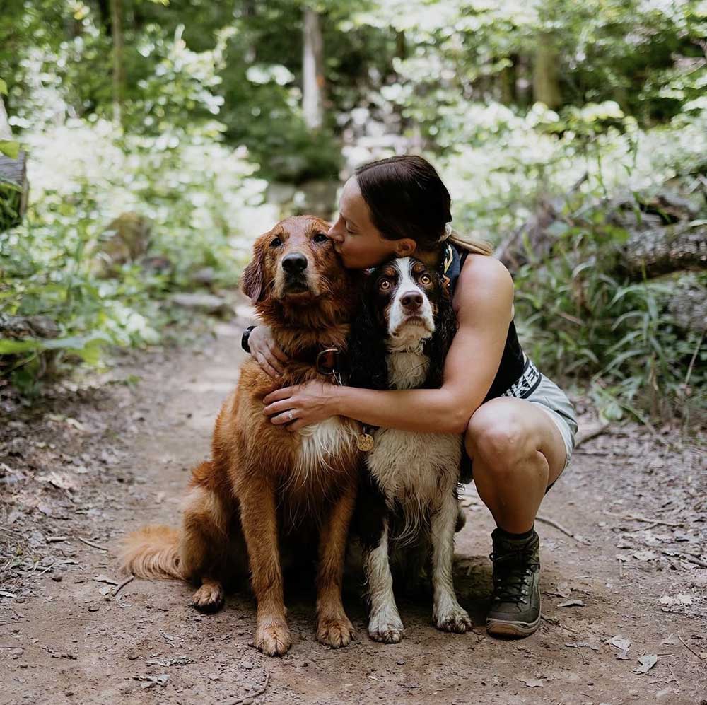 Woman kissing two dogs